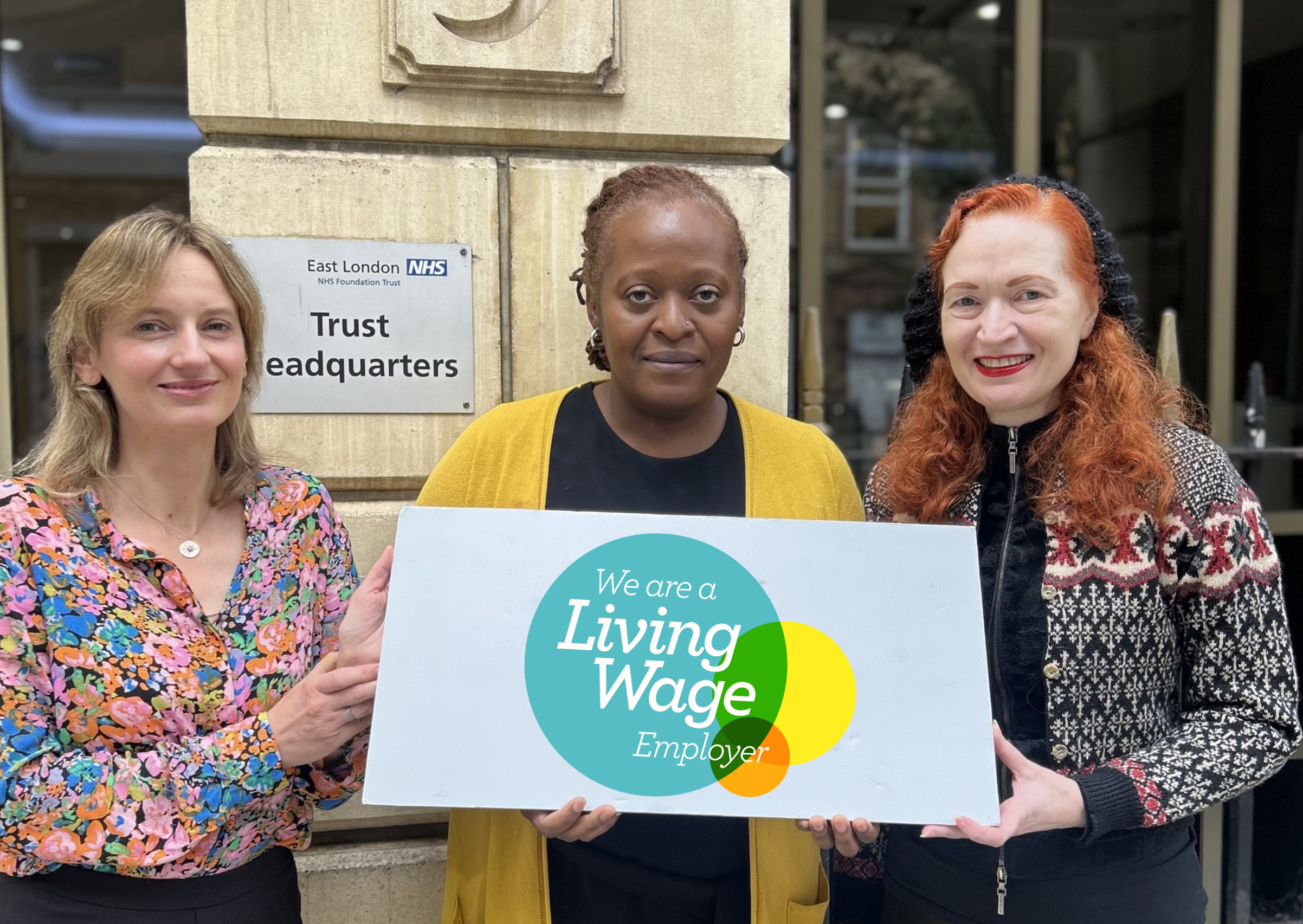 Left to right: Director of Population Health, Laura Austin Croft, ELFT Chief Executive, Lorraine Sunduza OBE and People Participation Cost of Living Lead, Susan Downing holding a living wage plaque. 