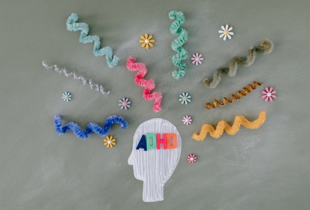 The words ADHD inside a human head shape, with several different coloured materials surrounding the head