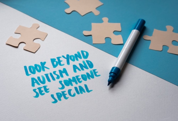 The words "Look beyond Autism and see someone special" are written in blue on a white table alongside some jigsaw pieces