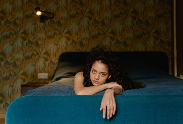 A woman lying on her bed giving a somewhat empty look