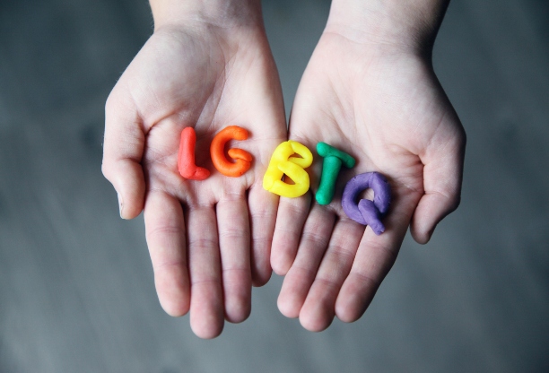 Two hands holding the letters LGBTQ in different colours