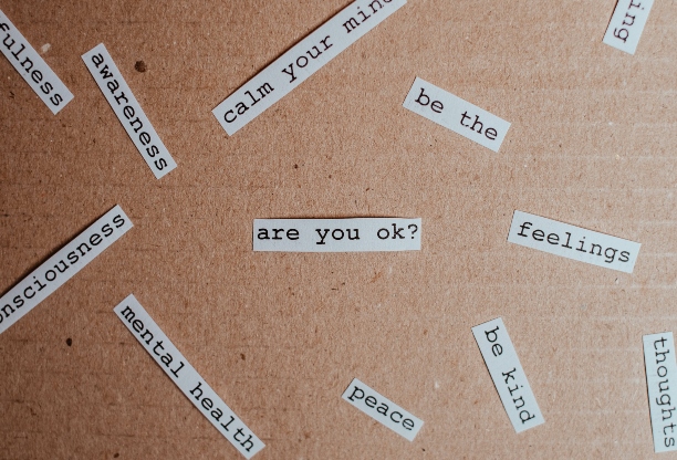 Various strips of paper with different mental health related words on them scattered on a surface