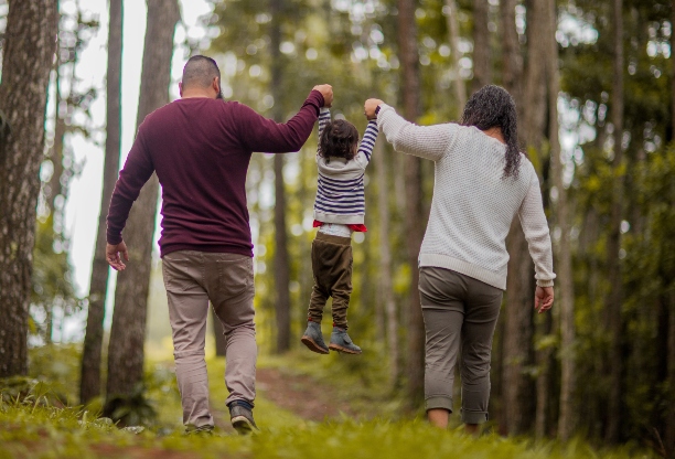 Two parents walking their child through a forest