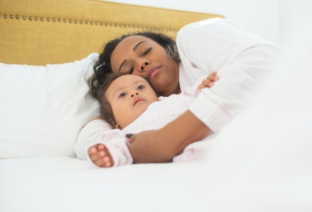 A parent and child in bed, with the child clearly awake