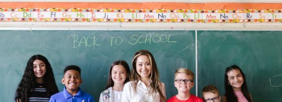 Children and Teacher standing infront of a blackboard