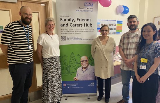 Staff in front of a Family, Friends and Carers hub banner.