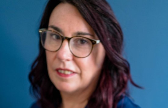 white female in blue dress with glasses